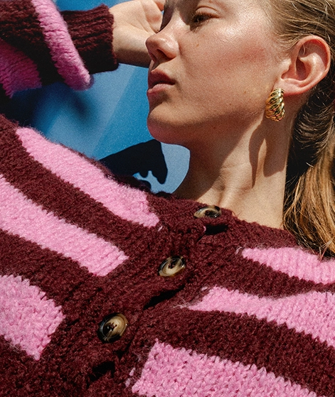 Nika trägt einen bordeauxrot-rosa gestreiften Strickcardigan; Zu Oberteile Damen gehen
