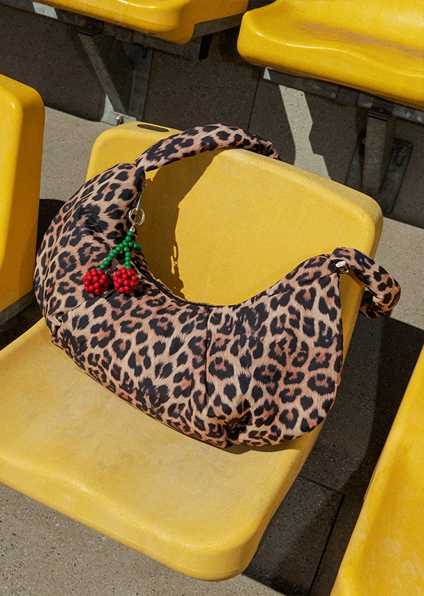 Eine große Leoprint-Tasche liegt auf einem gelben Sitz einer Stadiontribüne; Zu Taschen Damen gehen